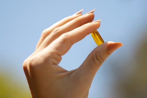 Hand holding mindbodygreen vitamin D3 supplement